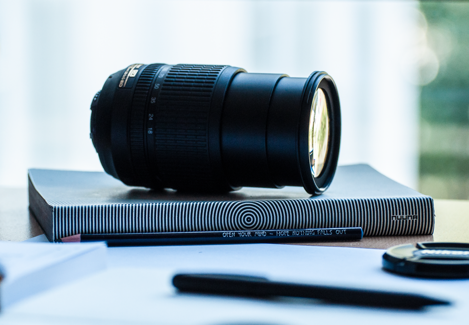 Camera lens resting on a stylish notebook, ideal for photography enthusiasts.